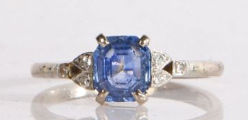 An 18 carat white gold sapphire and diamond ring, having a central emerald cut sapphire with diamond