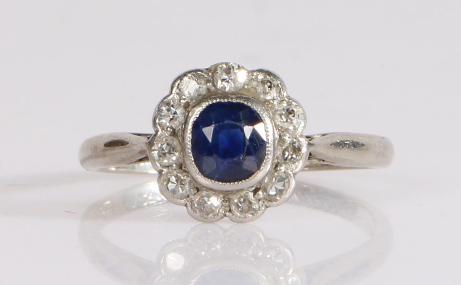 A sapphire and diamond cluster ring, the oval cut sapphire is bezel set, surrounded by old brilliant - Image 2 of 3