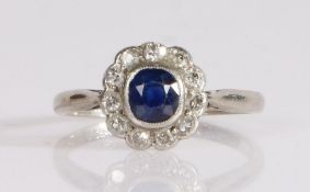 A sapphire and diamond cluster ring, the oval cut sapphire is bezel set, surrounded by old brilliant