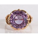 A purple stone set ring, the circular facetted stone within a yellow metal shank, 5.6 grams, ring