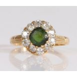 A diamond and gem set cluster ring, the central green stone is surrounded by old brilliant cut