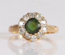 A diamond and gem set cluster ring, the central green stone is surrounded by old brilliant cut