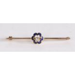 A diamond and enamel bar brooch, the central diamond with a blue enamel petal edge attached to the