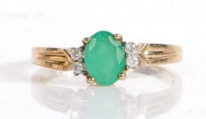 9 carat gold, emerald and diamond ring, the central claw set oval emerald flanked by two diamonds to