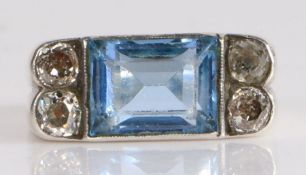 A silver, blue stone and diamond set ring, the central long emerald cut blue stone sits width ways