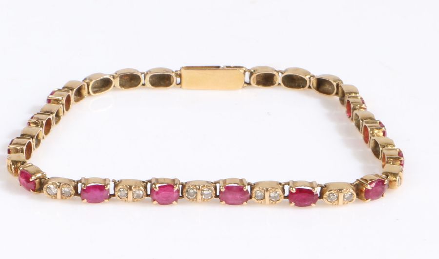 A yellow metal diamond and ruby bracelet, with claw mounted oval rubies intersected by diamonds,