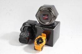 Two Casio G-Shock GA-100 gentleman's wristwatches, in yellow and black, both with tins, one with