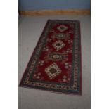 Middle Eastern style runner rug, the red and cream ground set with five guls and multiple