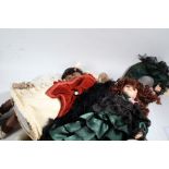 Collection of four modern porcelain dolls, one wearing a green and black dress with hat (4)