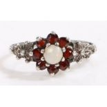 Silver white opal and garnet ring, the head set with claw mounted cabochon cut white opal surrounded