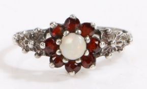 Silver white opal and garnet ring, the head set with claw mounted cabochon cut white opal surrounded