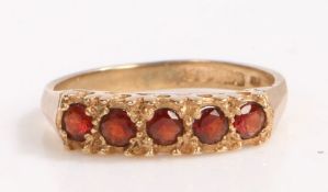 9 carat gold and garnet ring, the head set with five round cut garnets, ring size K weight 2.1 grams