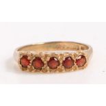 9 carat gold and garnet ring, the head set with five round cut garnets, ring size K weight 2.1 grams