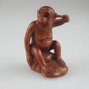 Netsuke - Buchsbaum geschnitzt, Affe hockt auf einem Felsbrocken und kratzt sich mit einem Stöckche