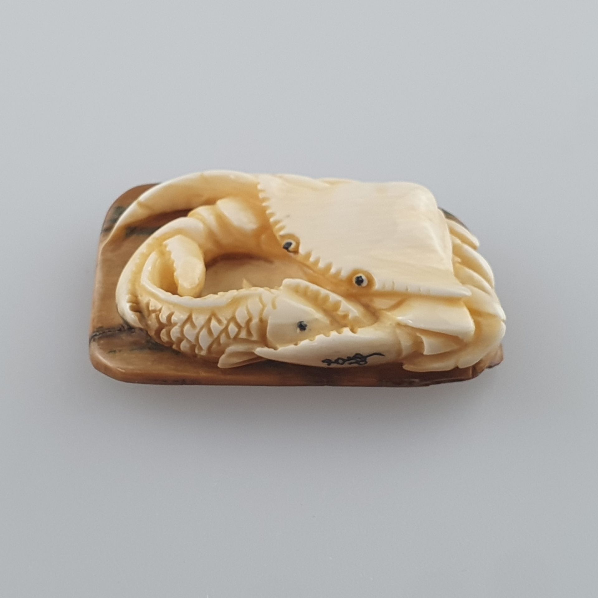 Netsuke - Mammutbein geschnitzt, graviert, Krabbe mit Fisch, signiert, Himotoshi auf der Unter