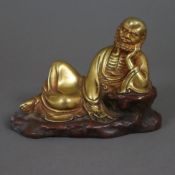Rastender Luohan/Arhat - China, Kupferlegierung, teils vergoldet, auf der Seite liegend, den Kopf a