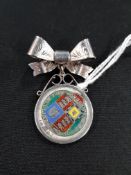 SILVER AND ENAMEL COIN PENDANT (VICTORIAN 1887) SUSPENDED FROM A SILVER BOW BROOCH