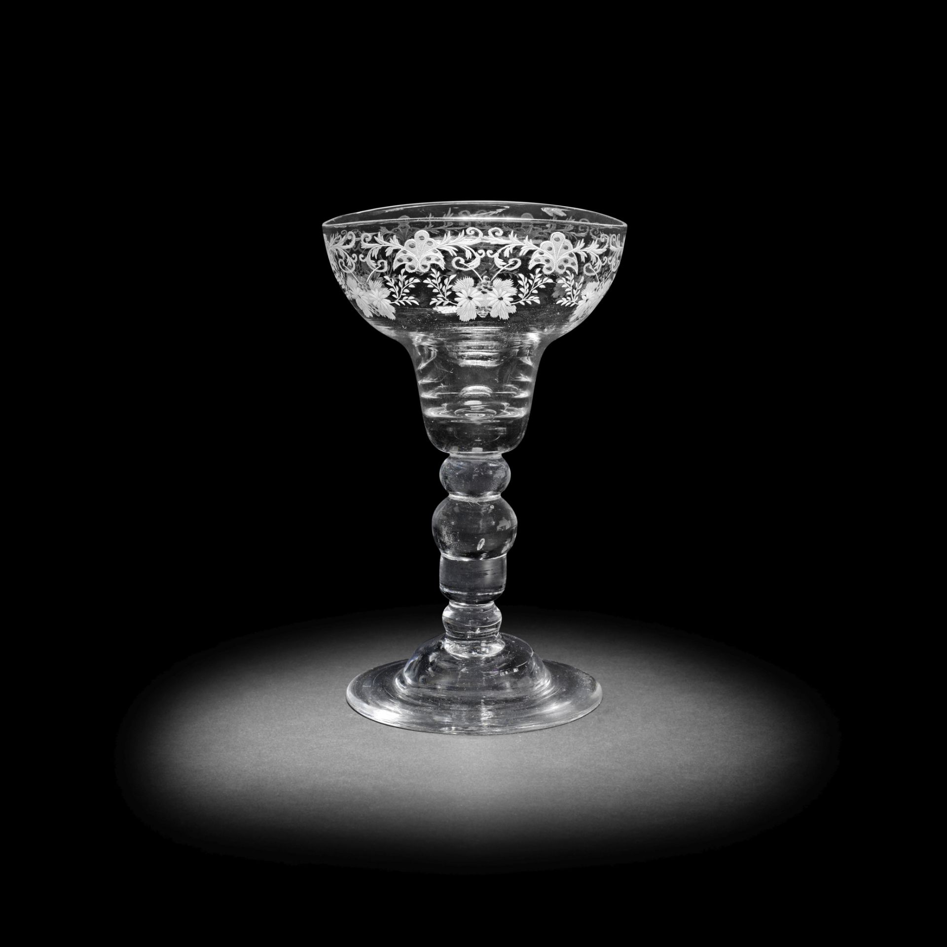 A very rare engraved acorn-knopped baluster sweetmeat or 'lemon' glass, circa 1730-40