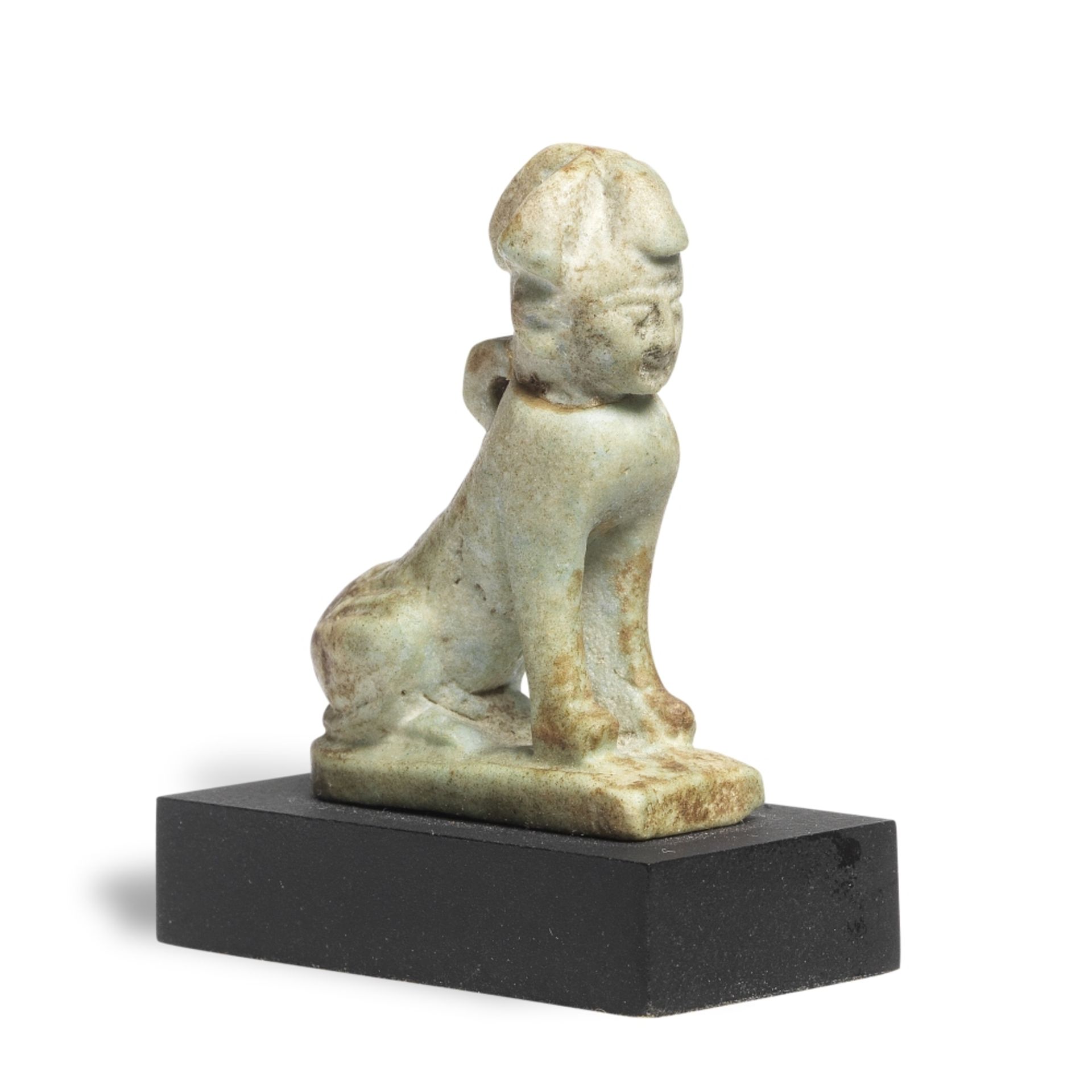 An Egyptian green glazed faience amulet of a seated Sphinx