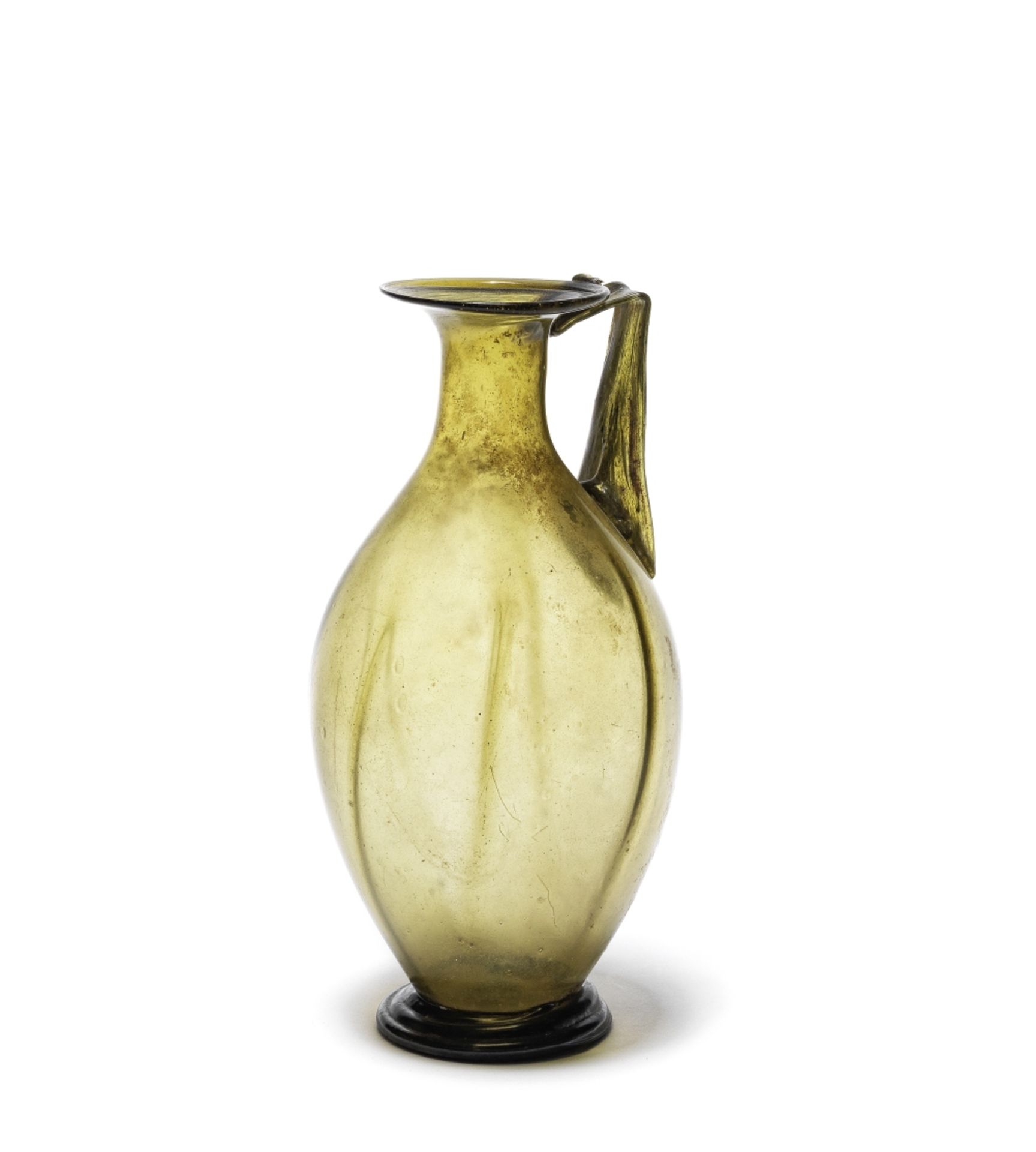 A Roman olive green glass ribbed jug