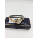 A 9ct gold cased ladies Tatton watch. Comes with an elasticated strap. In a working condition.
