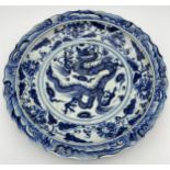A Large 20th century Chinese blue and white wall charger. Depicts dragon and floral design. Signed