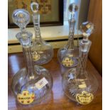 Four etched crystal decanters, with stoppers and labels; brandy, gin, port, whisky