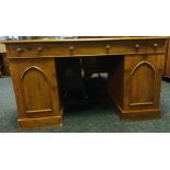 An oak knee-hole desk, the rounded rectangular top with green leather surface above three narrow