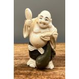 A Japanese Meiji period ivory carved netsuke of a laughing buddha holding a rat. [7cm in height]