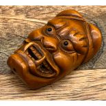 A Japanese hand carved Hannya mask netsuke. Designed with black bead eyes and signed. [5cm in