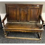 18th/19th century oak bench, the panelled back above open scroll arms and a rectangular seat, raised