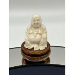 An early 20th century ivory carved Chinese Laughing Buddha sculpture. Sat on a wooden carved stand.