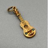 A Foreign gold guitar charm/ pendant. Fitted with turquoise style stones. Engraved to the back.