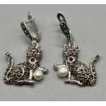 A Pair of silver cat earrings set with ruby eyes and pearl drops.