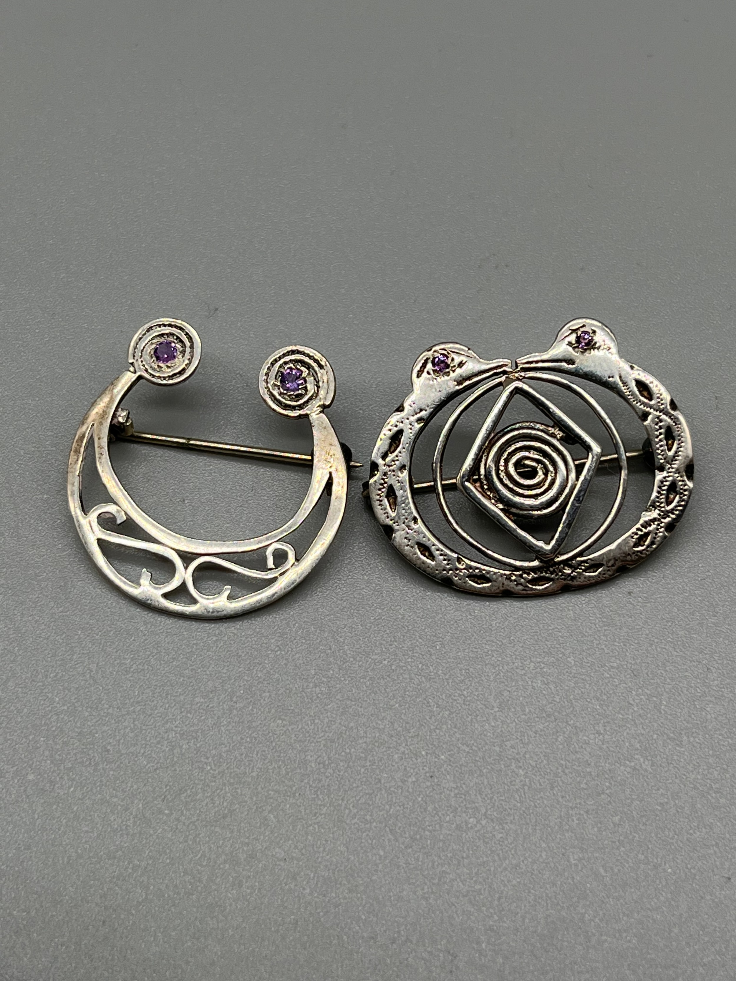 A Lot of two Irish Sterling silver clan/ plaid brooches. Both fitted with amethyst style stones.