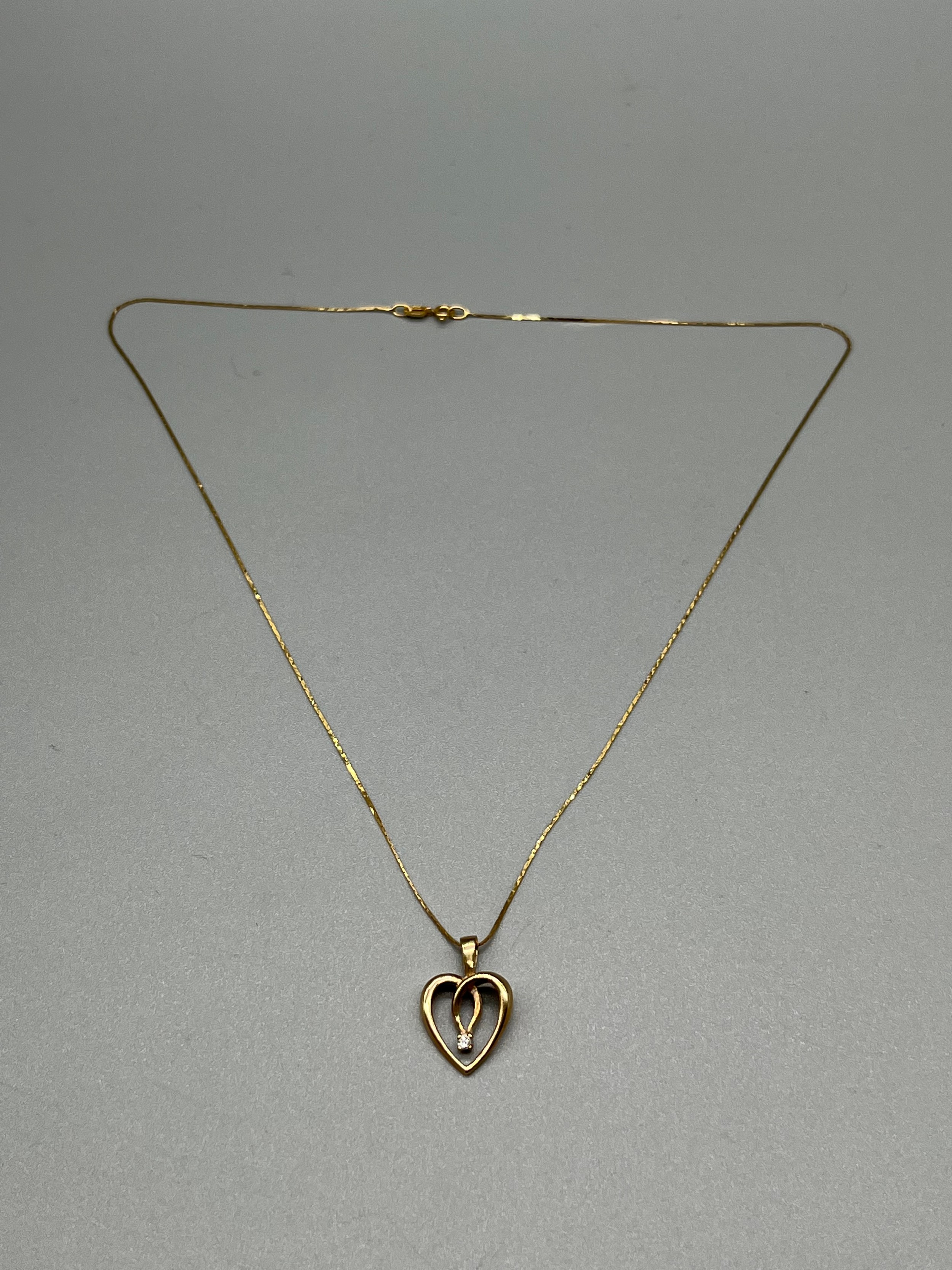 A 9ct gold heart shaped pendant set with a single diamond and comes with a 9ct gold necklace. [1.