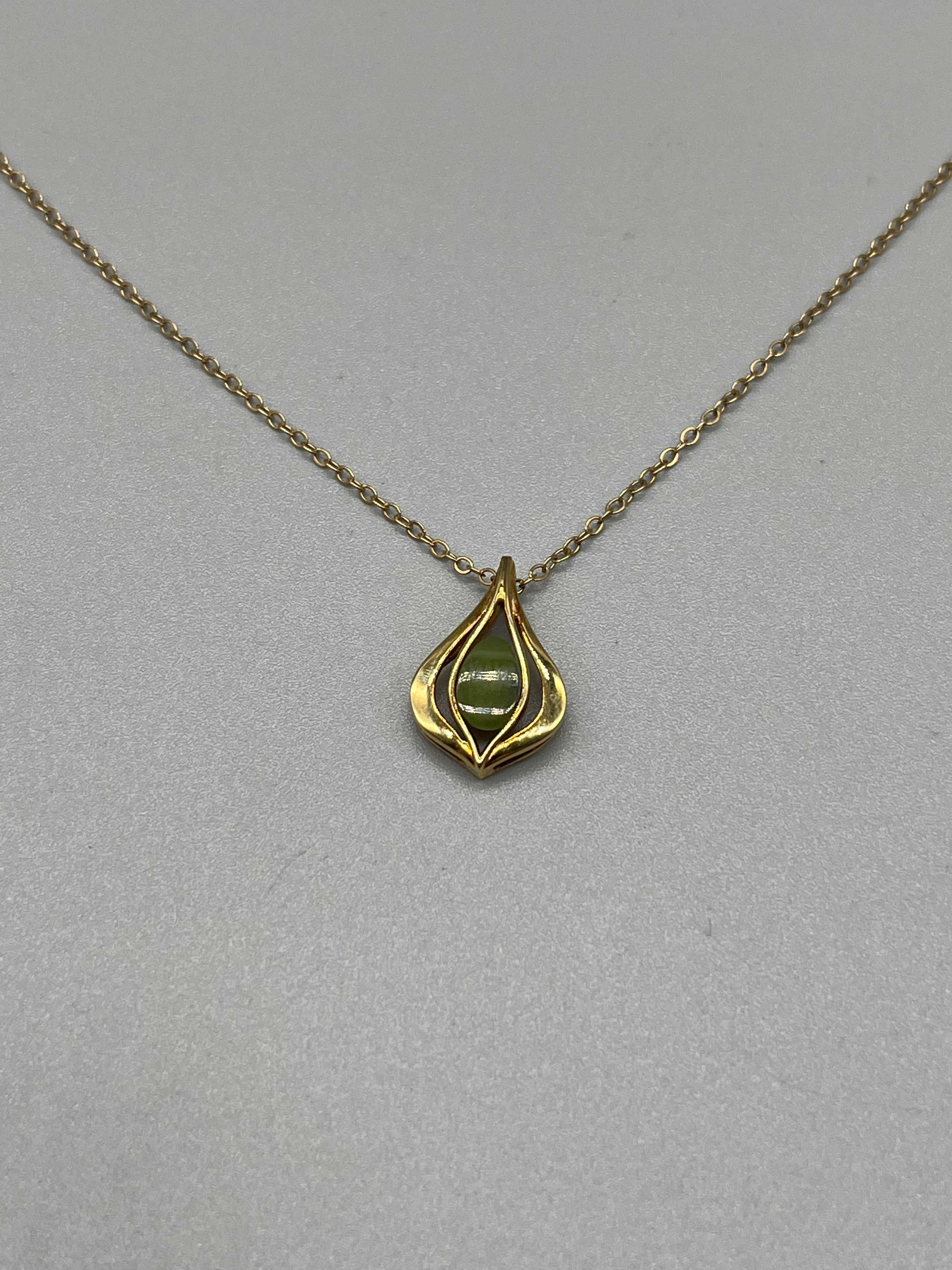 A 9ct gold pendant set with a jade stone and a 9ct gold necklace. [3.10grams]