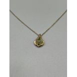A 9ct gold pendant set with a jade stone and a 9ct gold necklace. [3.10grams]