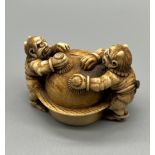 A Japanese Meiji period ivory netsuke, depicting two oni monsters cleaning a sphere. Signed to the