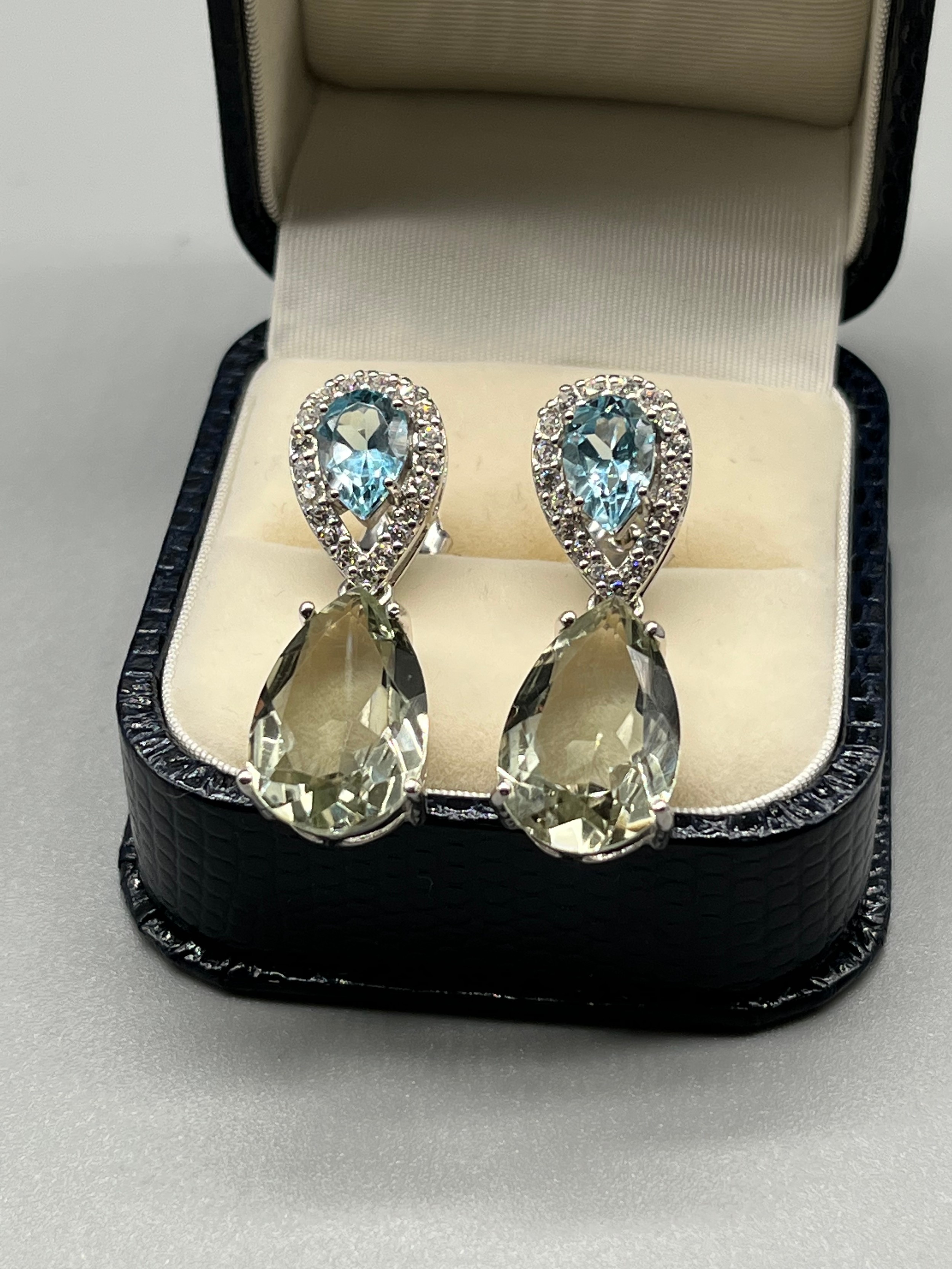 A Pair of silver, CZ and blue topaz drop earrings.