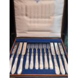 A Boxed set of twelve ornate knives and forks, designed with mother of pearl handles.