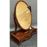 A George III Mahogany dressing mirror with oval plate and serpentine chequer banded base of three