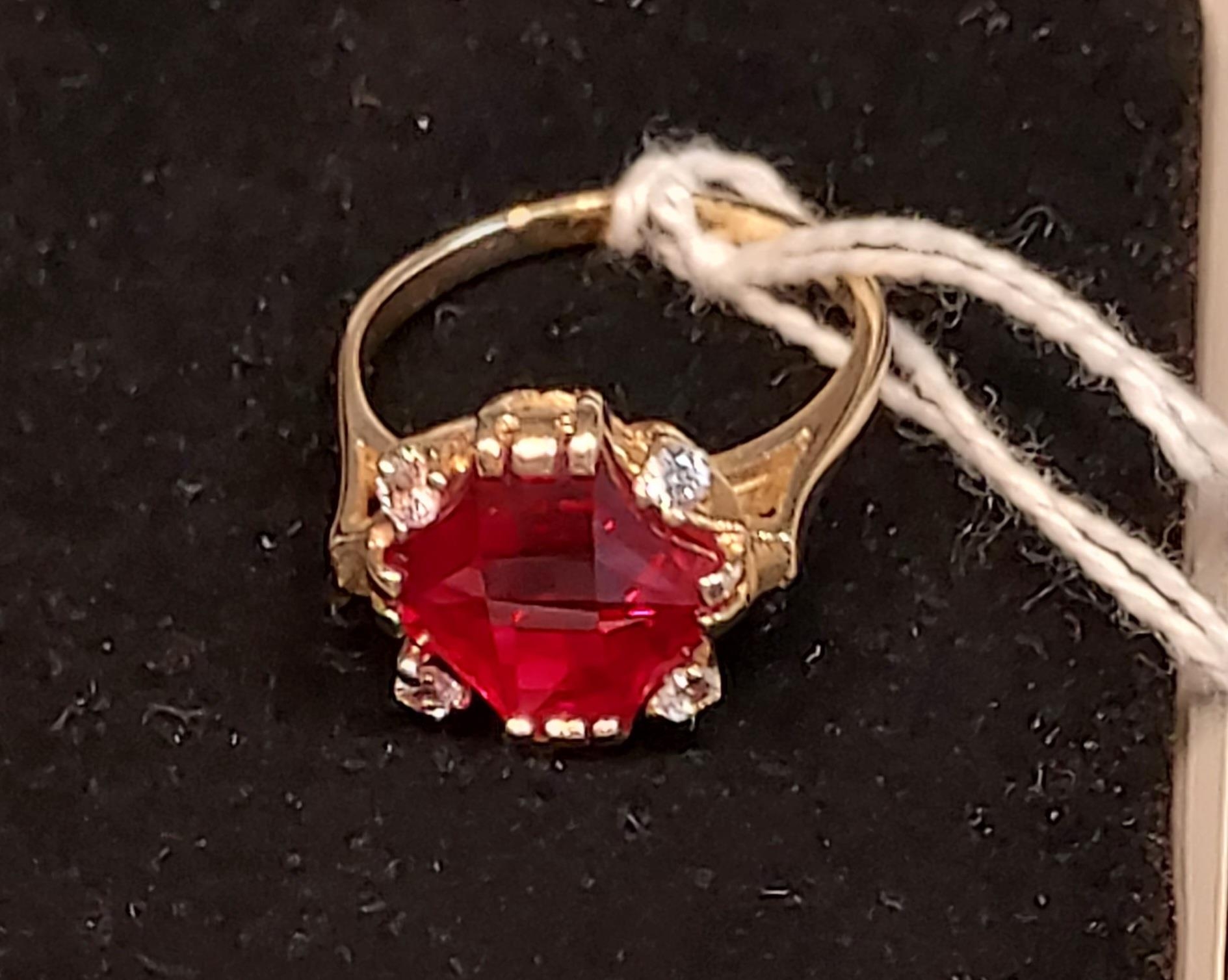 A 14ct yellow gold ring set with a large cut single ruby and four white spinel stones. [Ring size R]