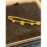 A Ladies antique 15ct gold bar brooch set with a single green tanzanite stone and off set by two