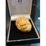 A Japanese hand carved tagua nut netsuke in the form of a foo dog gripping onto a rock. [4cm in