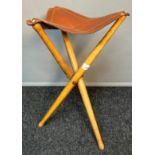 Cricket stool, the triangular brown leather top raised and supported on three turned legs