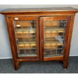 Arts and crafts bookcase, the moulded cornice above two framed doors opening to interior shelving