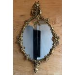 Antique Regency mirror, the moulded brass gilt frame surmounted by a floral and bow design [84x52cm]