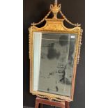 Antique mirror with moulded gilt frame, surmounted by a trophy and flanked by a trailing chain