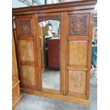 Arts & Crafts oak wardrobe, the moulded cornice above a mirrored door flanked by two additional